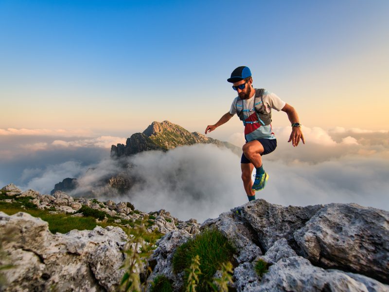 Man ultramarathon runner in the mountains he trains at sunset