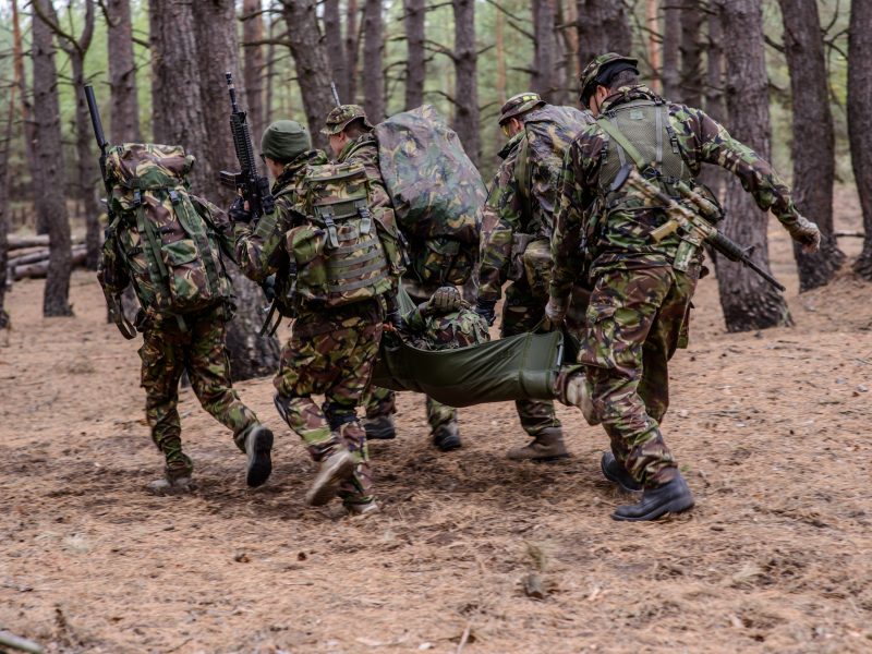 Soldiers run away from the battlefield with stretcher and wounde